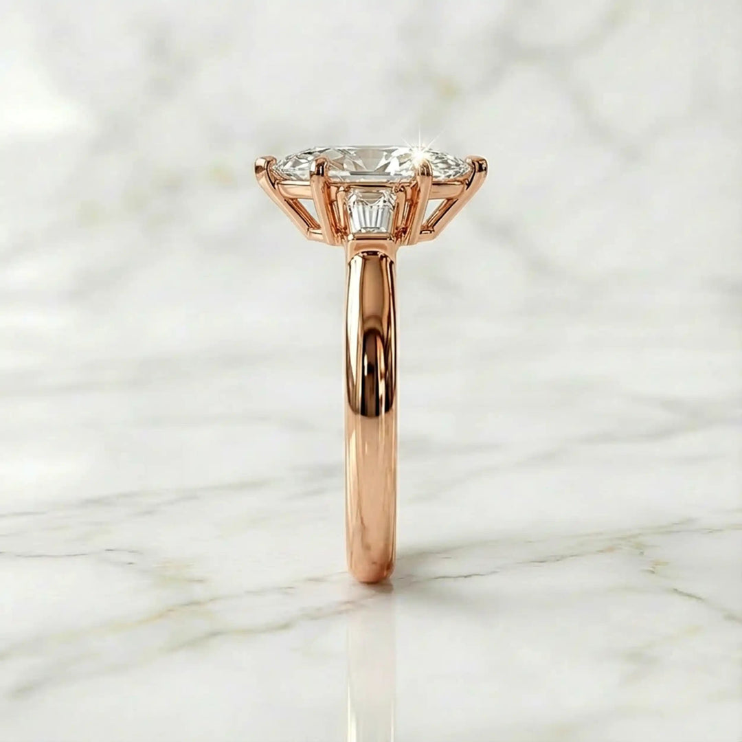 Three-stone marquise lab-grown diamond engagement ring displayed on marble surface.
