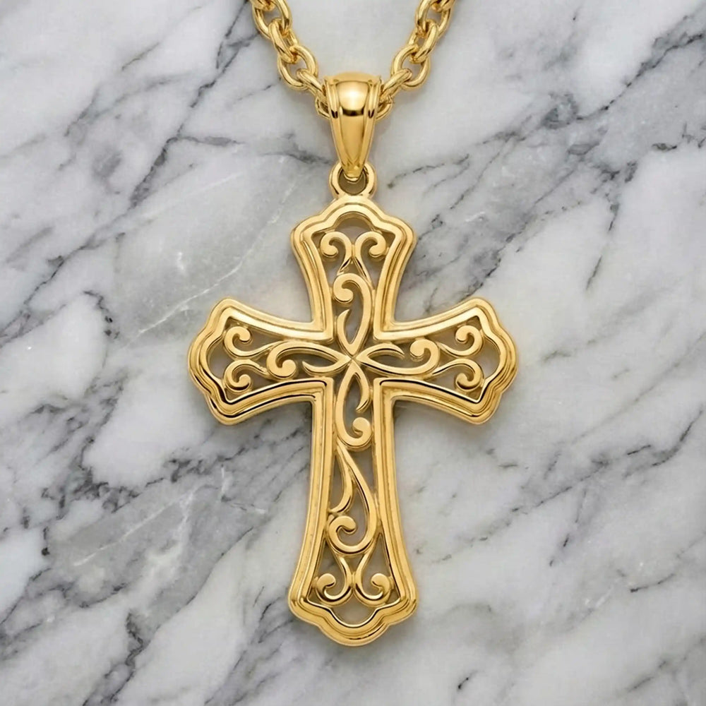 Victorian hollow cross pendant with intricate scrollwork displayed on chain over marble background.