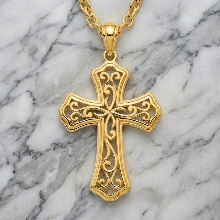 Ornate filigree Latin cross pendant necklace displayed on marble background.