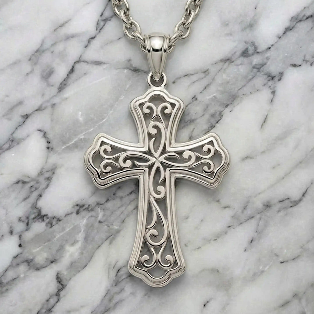 Ornate filigree Latin cross pendant necklace displayed on marble background.