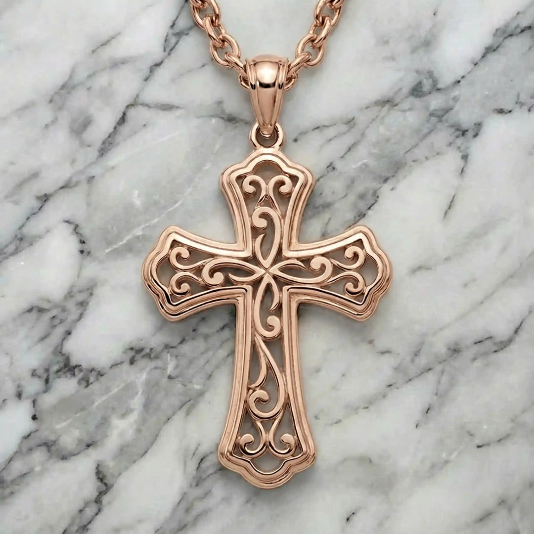 Ornate filigree Latin cross pendant necklace displayed on marble background.