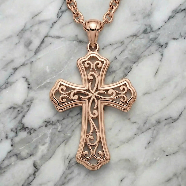 Ornate filigree Latin cross pendant necklace displayed on marble background.