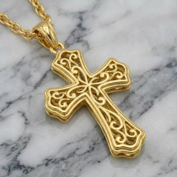 Victorian hollow cross pendant with intricate scrollwork displayed on chain over marble background.
