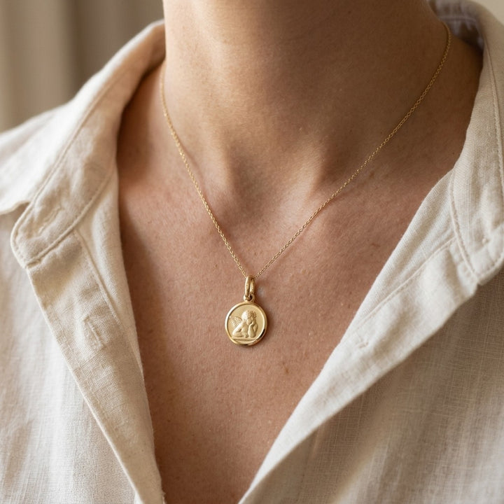 Yellow Gold Angel Medal worn on a model's neck on a fine chain