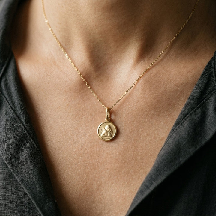Yellow Gold Angel Medal worn on a model's neck on a fine chain