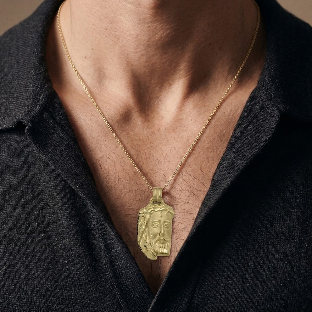 Yellow gold Jesus head pendant with a crown of thorns, flowing hair and a diamond-cut beard, 25.8 mm wide and 39.4 mm tall, worn by a man on a fine yellow gold chain
